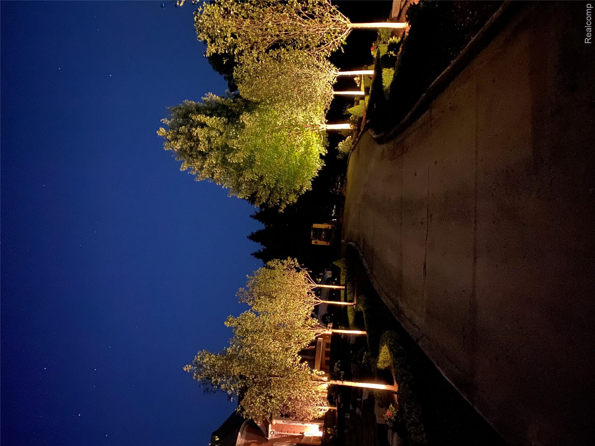 5165 Abbey Drive Rochester, MI 48306 - Photo 4 of 66 Paved driveway framed by mature trees with landscape lighting, illuminating a portion of the property's exterior
