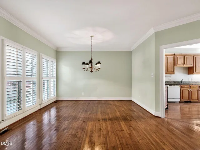 a view of an empty room with window wooden floor and a kitchen