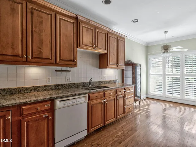 a kitchen with stainless steel appliances granite countertop a stove a sink dishwasher and cabinets with wooden floor