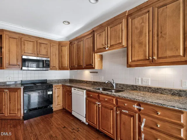 a kitchen with stainless steel appliances granite countertop a stove a sink dishwasher and a microwave oven with wooden cabinets