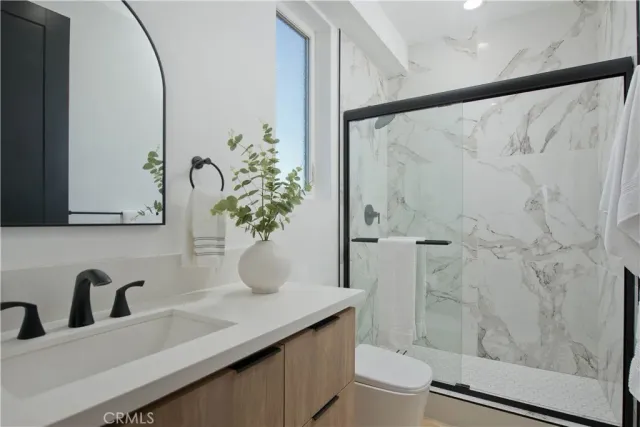 a bathroom with a granite countertop sink a mirror and shower