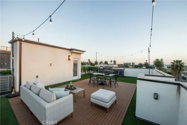 a view of a roof deck with couches and potted plants with wooden floor