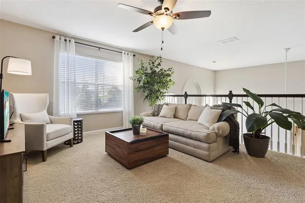 a living room with furniture a ceiling fan and a window