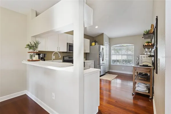a kitchen with stainless steel appliances wooden floor and a refrigerator