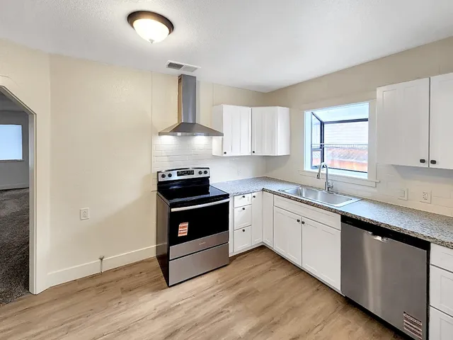 a kitchen with granite countertop wooden floors and white stainless steel appliances