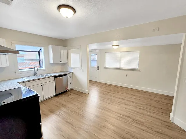 a large kitchen with wooden floors and white cabinets