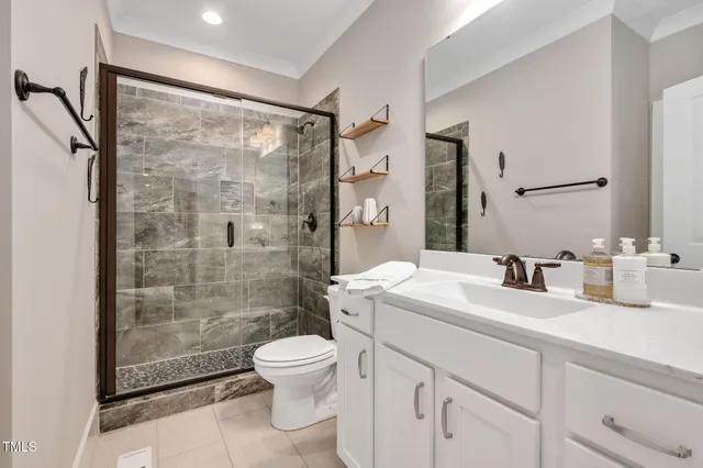 a bathroom with a shower sink vanity mirror and toilet