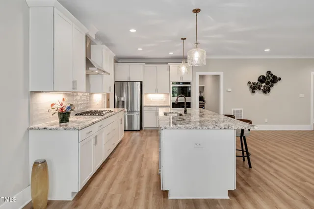 a kitchen with stainless steel appliances granite countertop sink stove refrigerator and couches