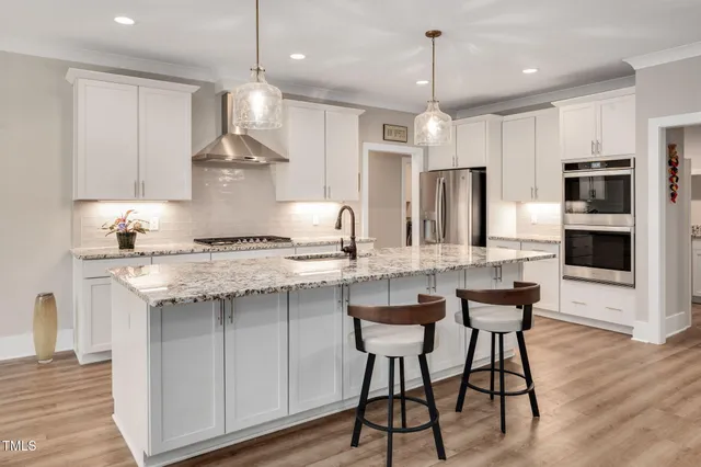 a kitchen with granite countertop kitchen island stainless steel appliances a sink and a refrigerator