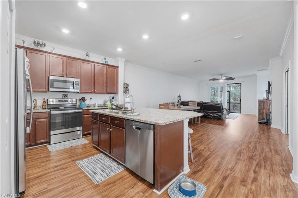 9052 Glenforest Drive Naples, FL 34120 - Photo 3 of 20 a kitchen with kitchen island granite countertop wooden floors and stainless steel appliances