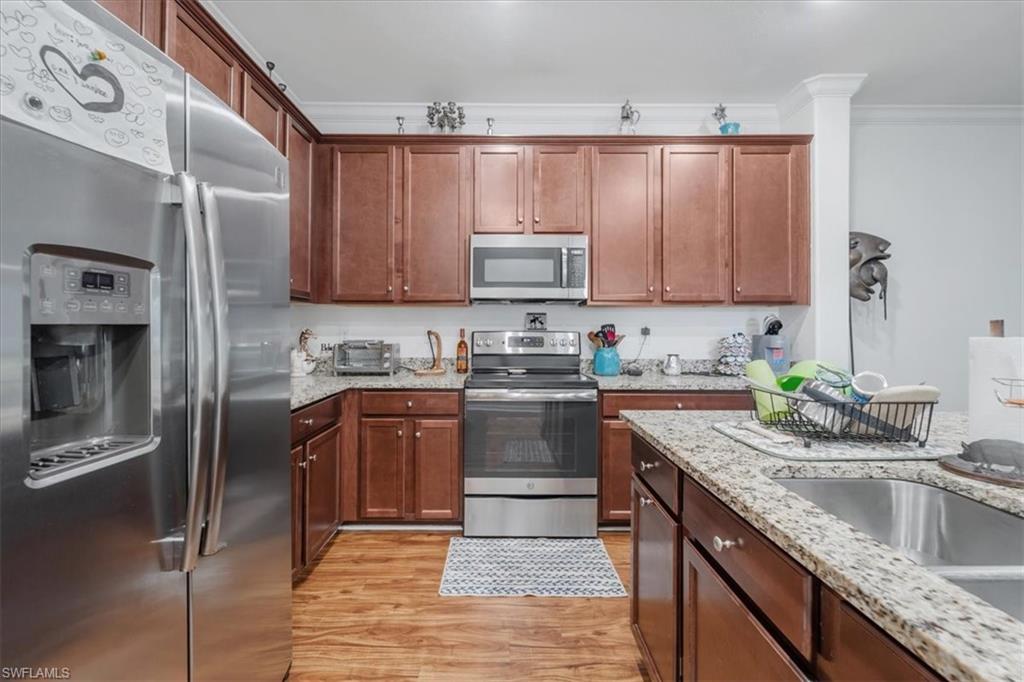 9052 Glenforest Drive Naples, FL 34120 - Photo 4 of 20 a kitchen with stainless steel appliances granite countertop a sink stove and refrigerator