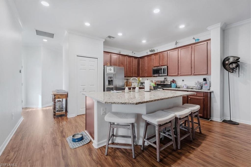 9052 Glenforest Drive Naples, FL 34120 - Photo 5 of 20 a kitchen with kitchen island granite countertop a dining table chairs refrigerator and cabinets