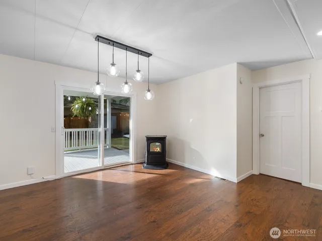 an empty room with wooden floor fireplace and windows