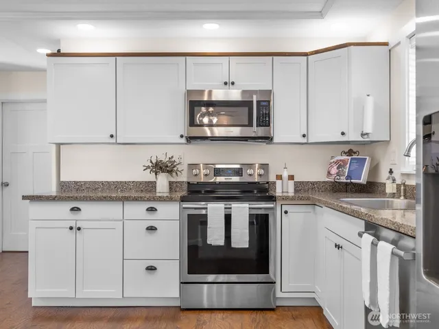 a kitchen with stainless steel appliances granite countertop a stove a sink and a microwave