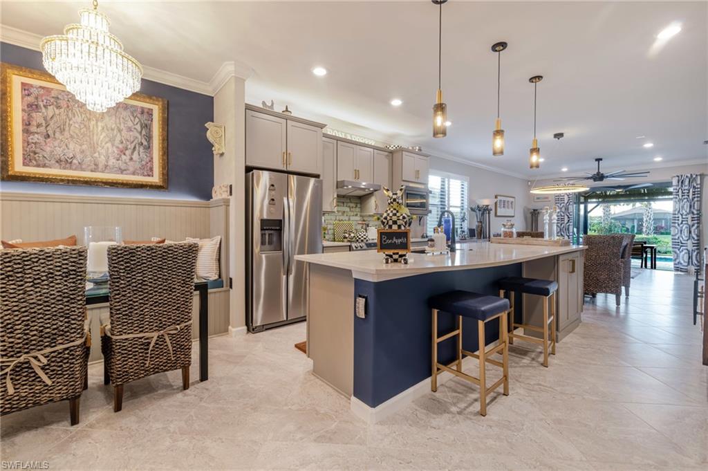 Kitchen with crown molding, stainless steel refrigerator with ice dispenser, gray cabinets, a ceiling fan, and a chandelier