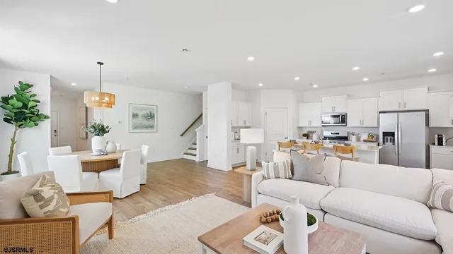 a living room with furniture kitchen view and a chandelier