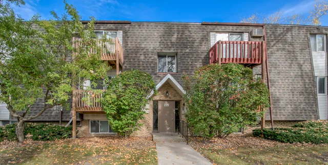 a pathway of a house with potted plants and wooden fence