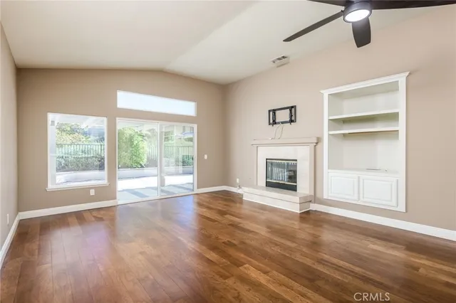 a view of an empty room with a window and wooden floor