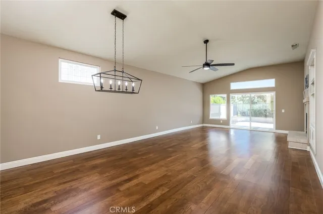 a view of a room with wooden floor chandelier and windows