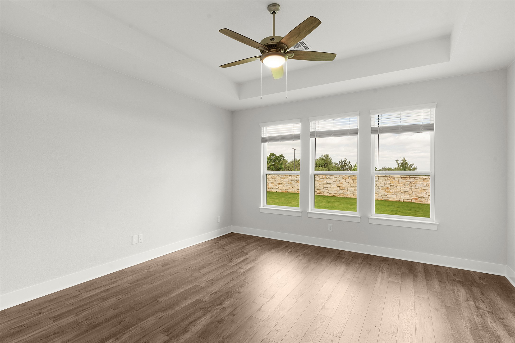 1129 Pansy Trail Georgetown, TX 78628 - Photo 16 of 29 Room featuring wood-finish flooring, a tray ceiling, and a ceiling fan with integrated lighting
