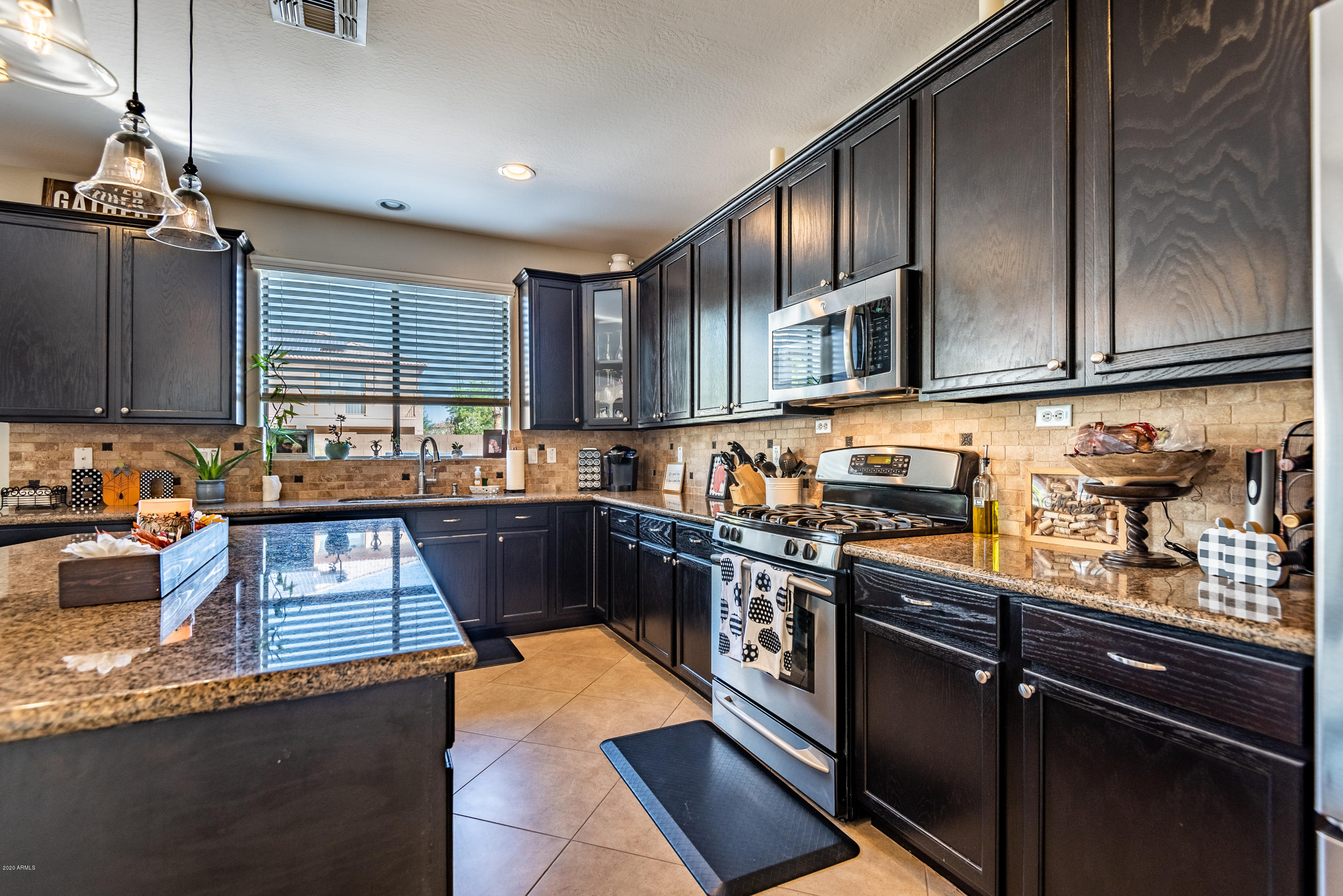 13628 West Calavar Road Surprise, AZ 85379 - Photo 13 of 48 a kitchen with stainless steel appliances granite countertop a stove a sink dishwasher and cabinets with wooden floor