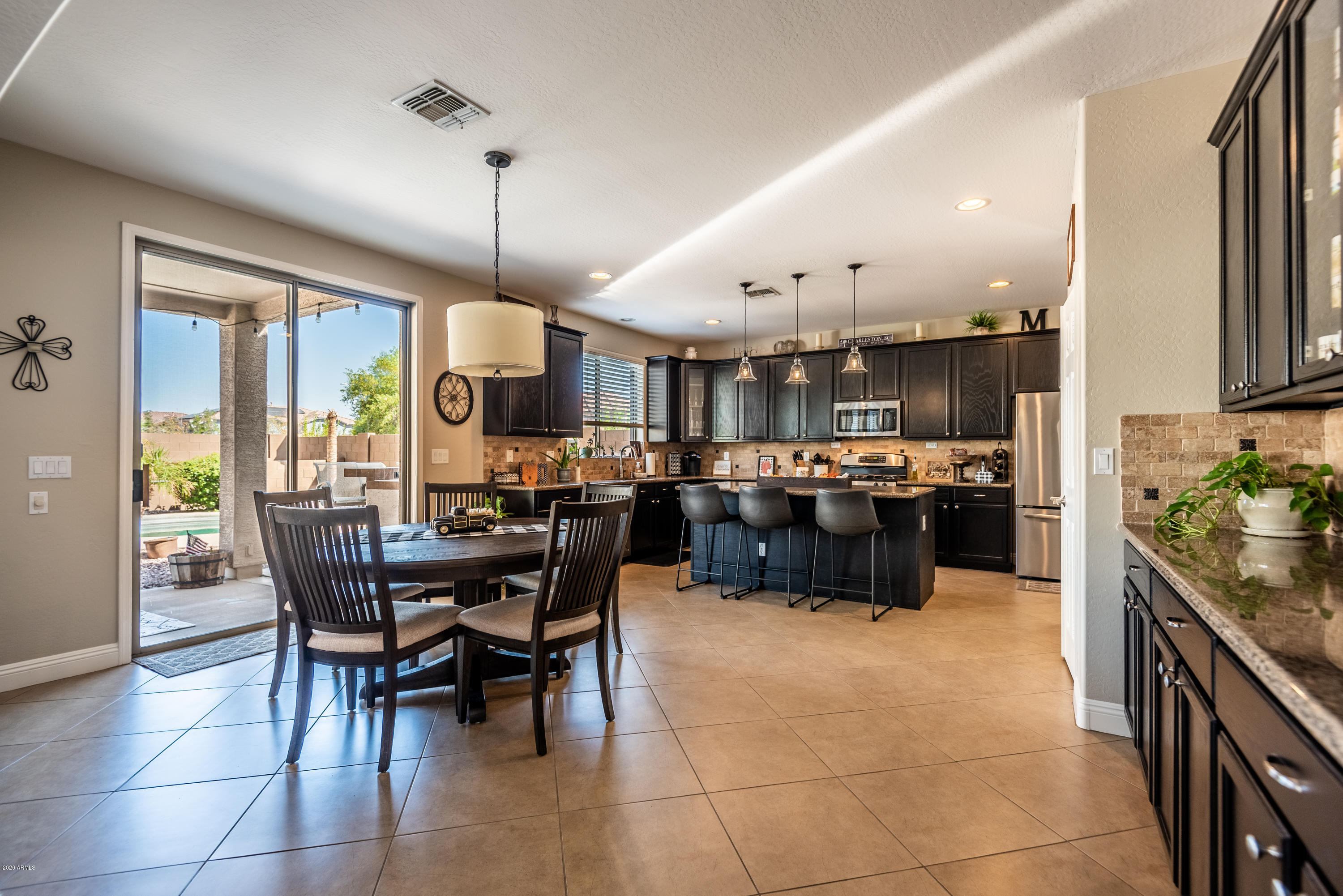 13628 West Calavar Road Surprise, AZ 85379 - Photo 9 of 48 a kitchen with kitchen island a stove a table and chairs in it