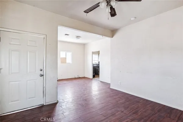 an empty room with wooden floor cabinet and windows