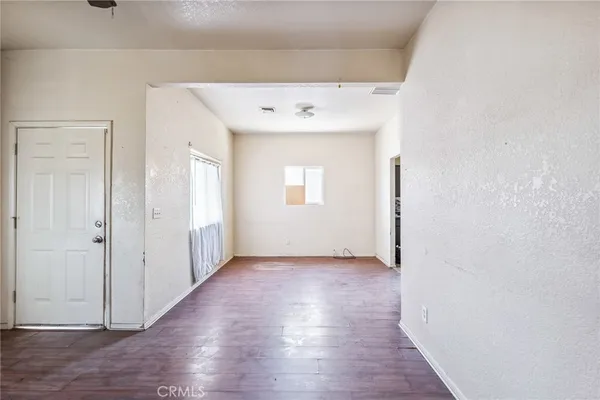 an empty room with wooden floor and mirror