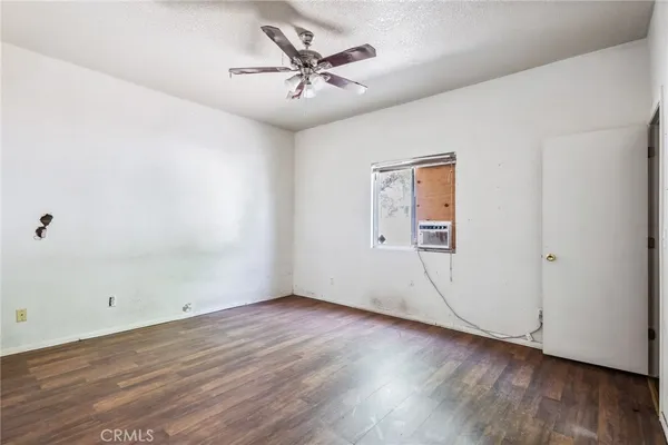 an empty room with wooden floor and ceiling fan