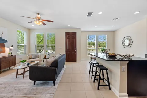 a living room with furniture kitchen view and a chandelier