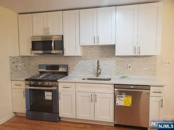 a kitchen with granite countertop white cabinets and stainless steel appliances