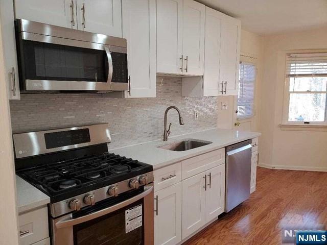 27 Ridge Road Cresskill, NJ 07626 - Photo 6 of 18 a kitchen with stainless steel appliances a sink a stove and microwave