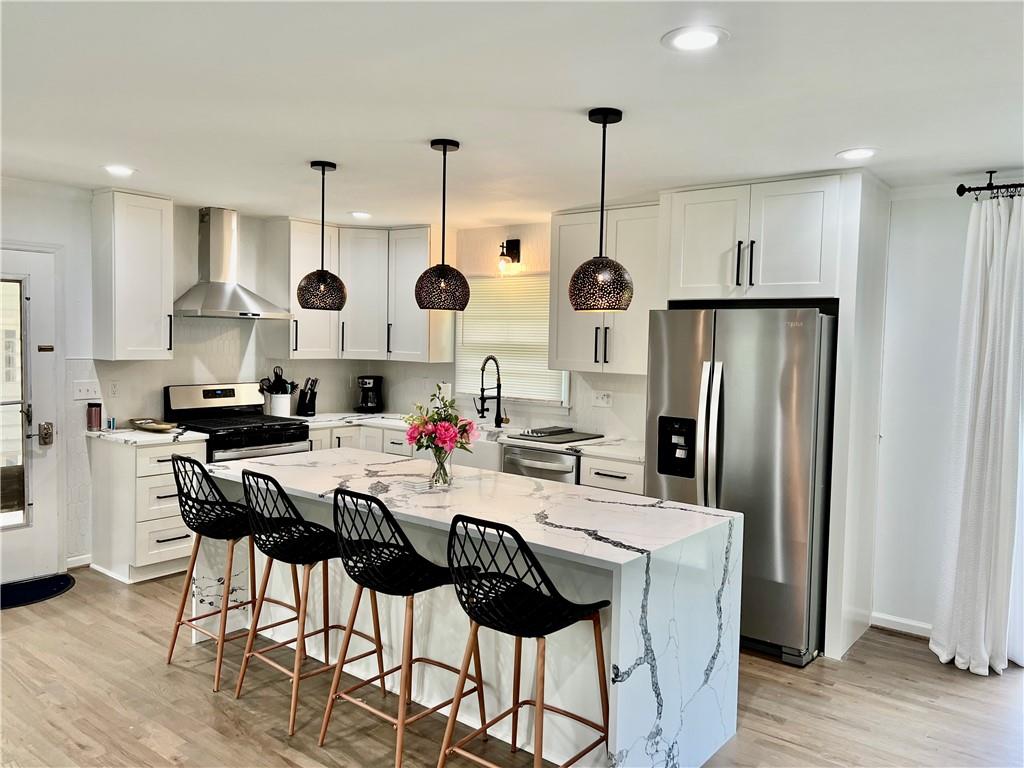 a kitchen with stainless steel appliances kitchen island granite countertop a refrigerator a stove a sink dishwasher and a dining table with wooden floor