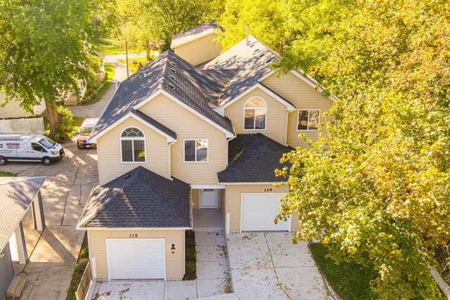a view of a white house next to a yard with large trees