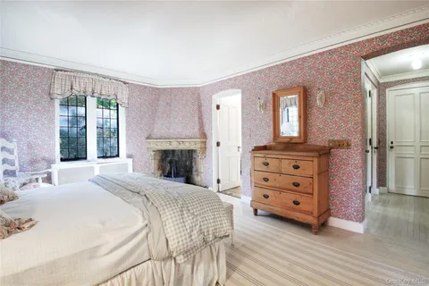 a spacious bedroom with a bed a dresser and a large window