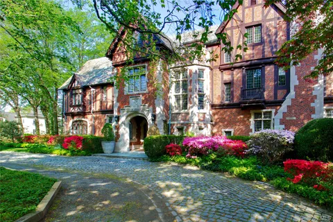 a front view of multi story residential apartment building with yard and flowers
