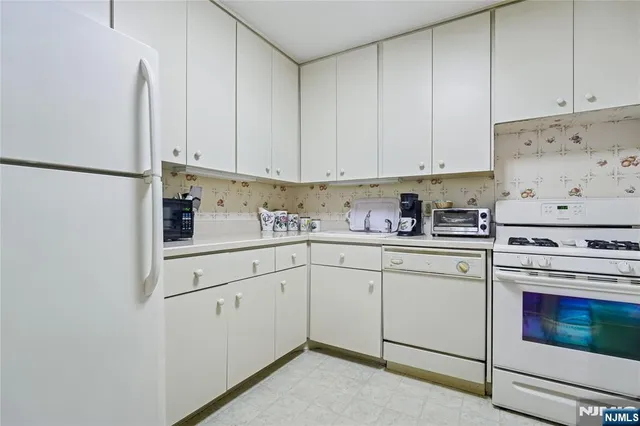 a kitchen with granite countertop white cabinets and white appliances