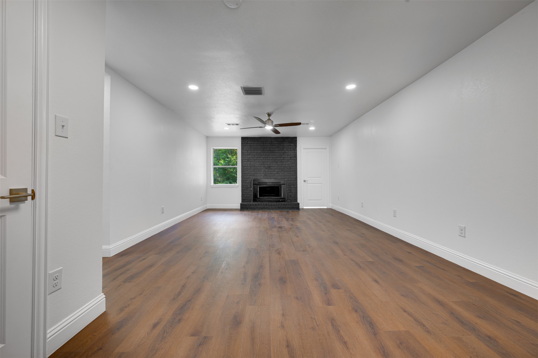 302 An County Road 3914 Palestine, TX 75801 - Photo 5 of 44 an empty room with wooden floor a fireplace and windows