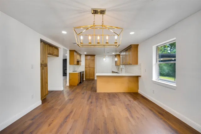 a large kitchen with stainless steel appliances granite countertop a dishwasher a stove a sink dishwasher and a fireplace with wooden floor