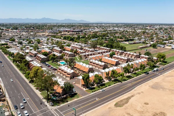 an aerial view of a tennis ground and a cars park side of the road