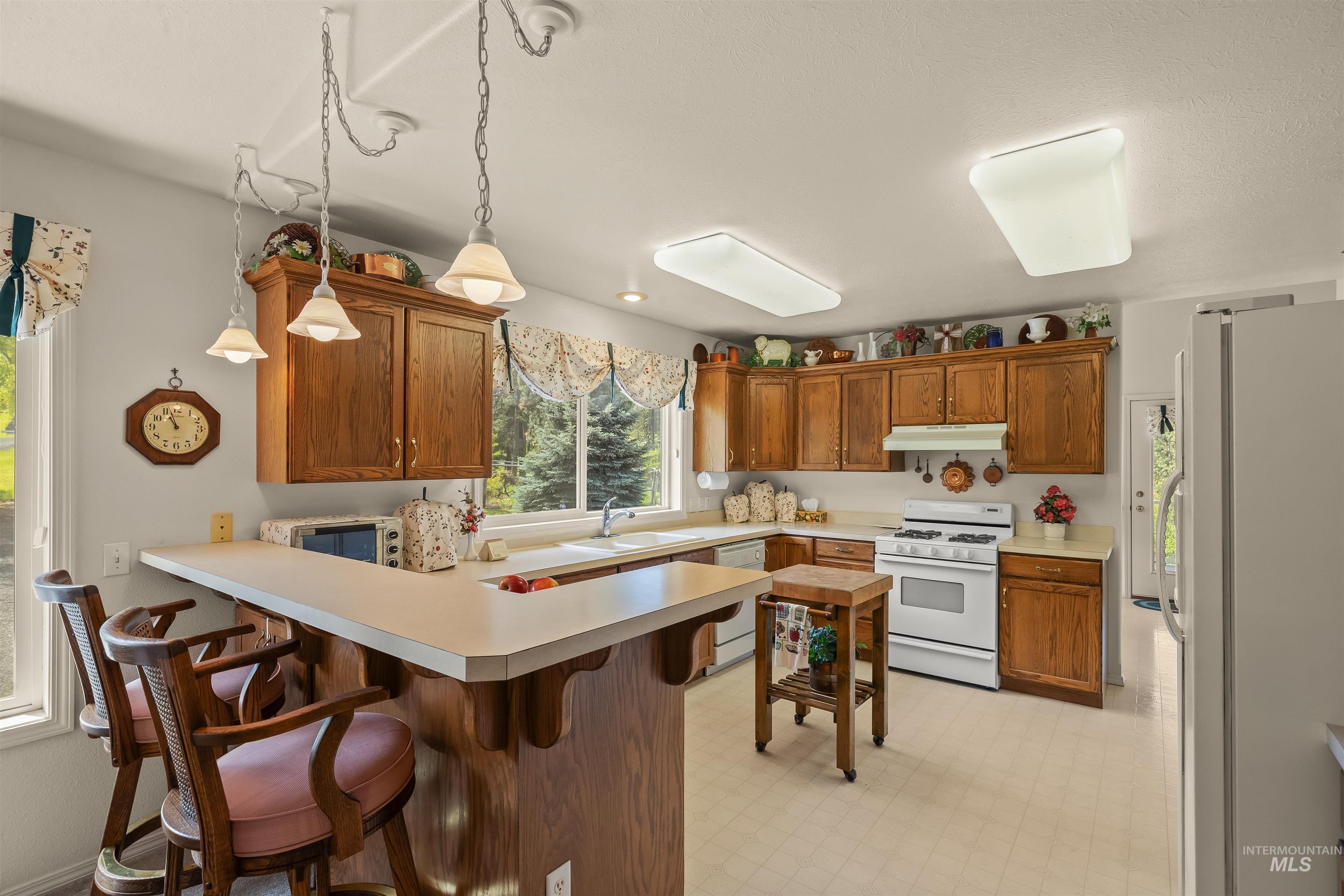 743 Wall Crk Road Stites, ID 83552 - Photo 27 of 48 L-shaped kitchen featuring wood cabinetry and white appliances