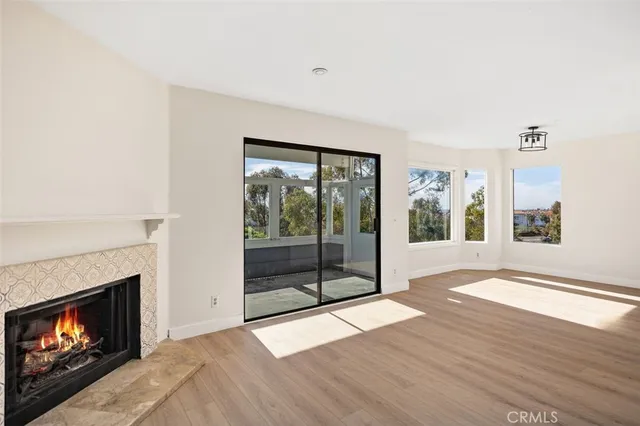 a view of an empty room with wooden floor fireplace and a window