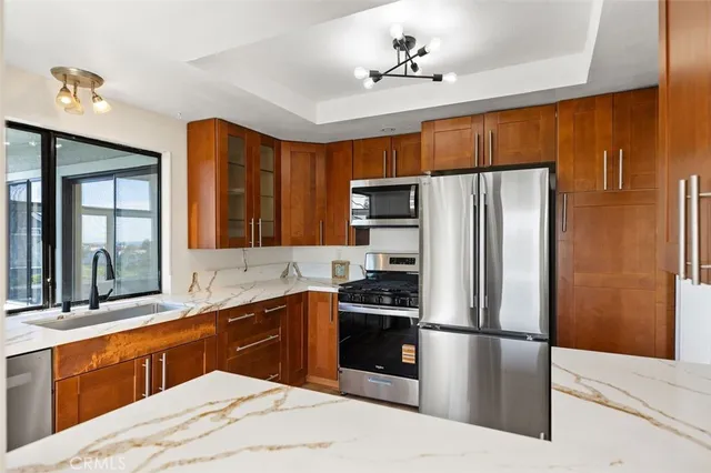 a kitchen with stainless steel appliances a sink a stove a refrigerator cabinets and a window