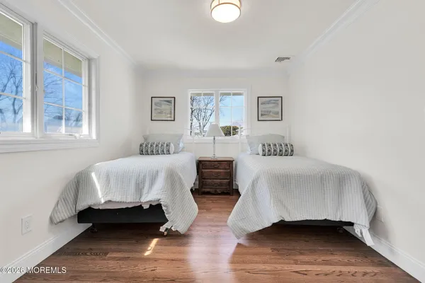 a spacious bedroom with a bed a mirror and a large window with wooden floor