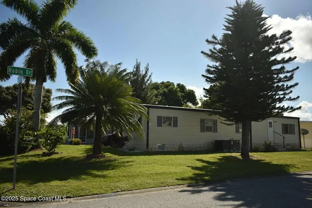 a view of a house with a yard and palm trees