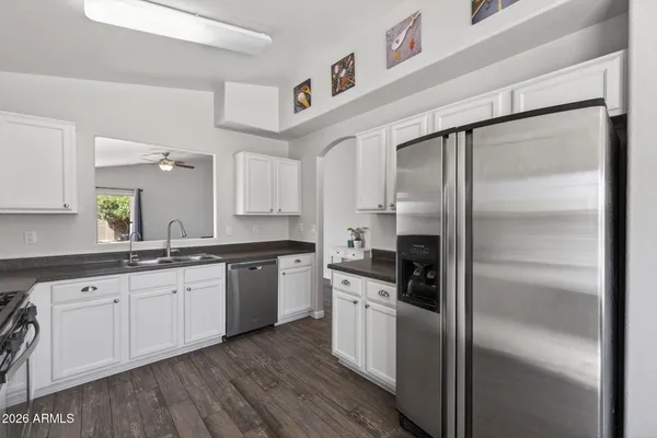 a kitchen with granite countertop stainless steel appliances a refrigerator a sink and cabinets