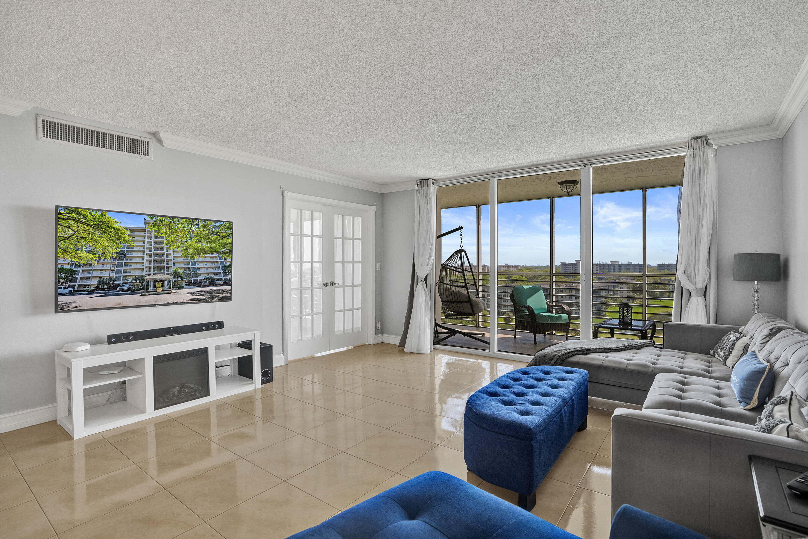 3520 Oaks Way, Unit 1010 Pompano Beach, FL 33069 - Photo 26 of 67 a living room with furniture a flat screen tv and a floor to ceiling window