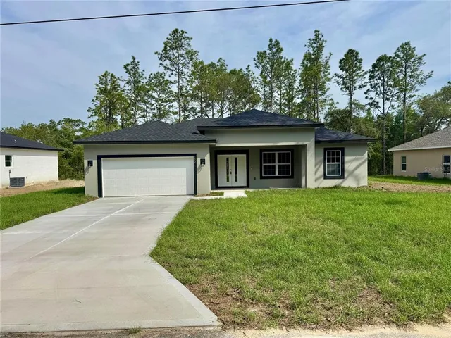 a front view of a house with a garden and trees