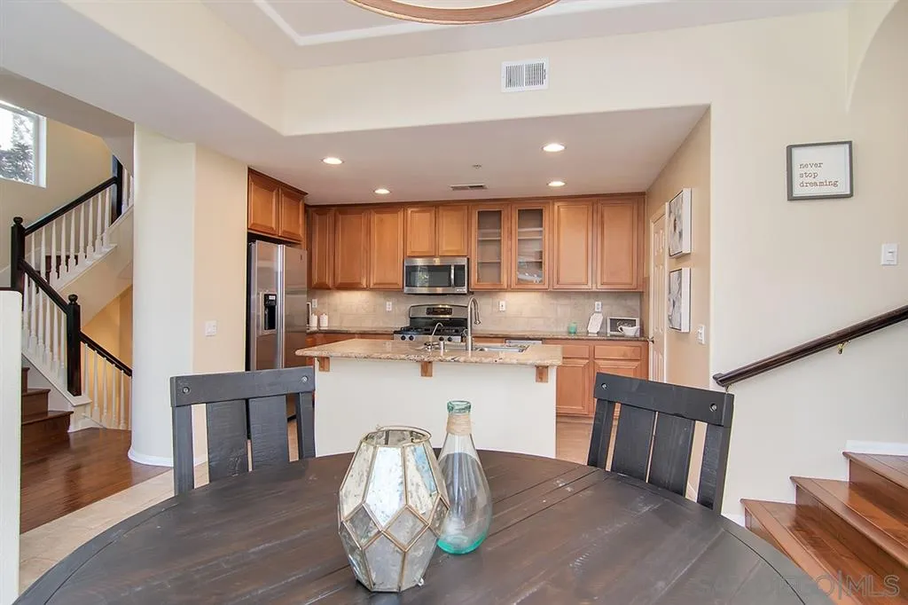 2230 Historic Decatur Road, Unit 63 San Diego, CA 92106 - Photo 6 of 25 a kitchen with stainless steel appliances granite countertop a refrigerator a stove a sink and a dining table with wooden floor