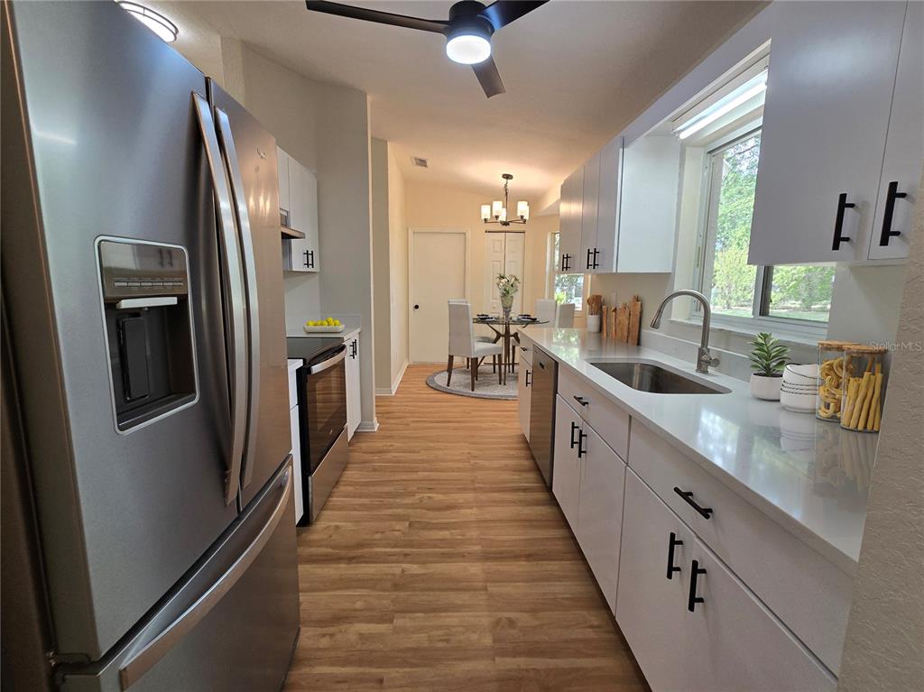 6121 Southwest 103rd Loop Ocala, FL 34476 - Photo 13 of 32 a large white kitchen with a large window a sink and stainless steel appliances